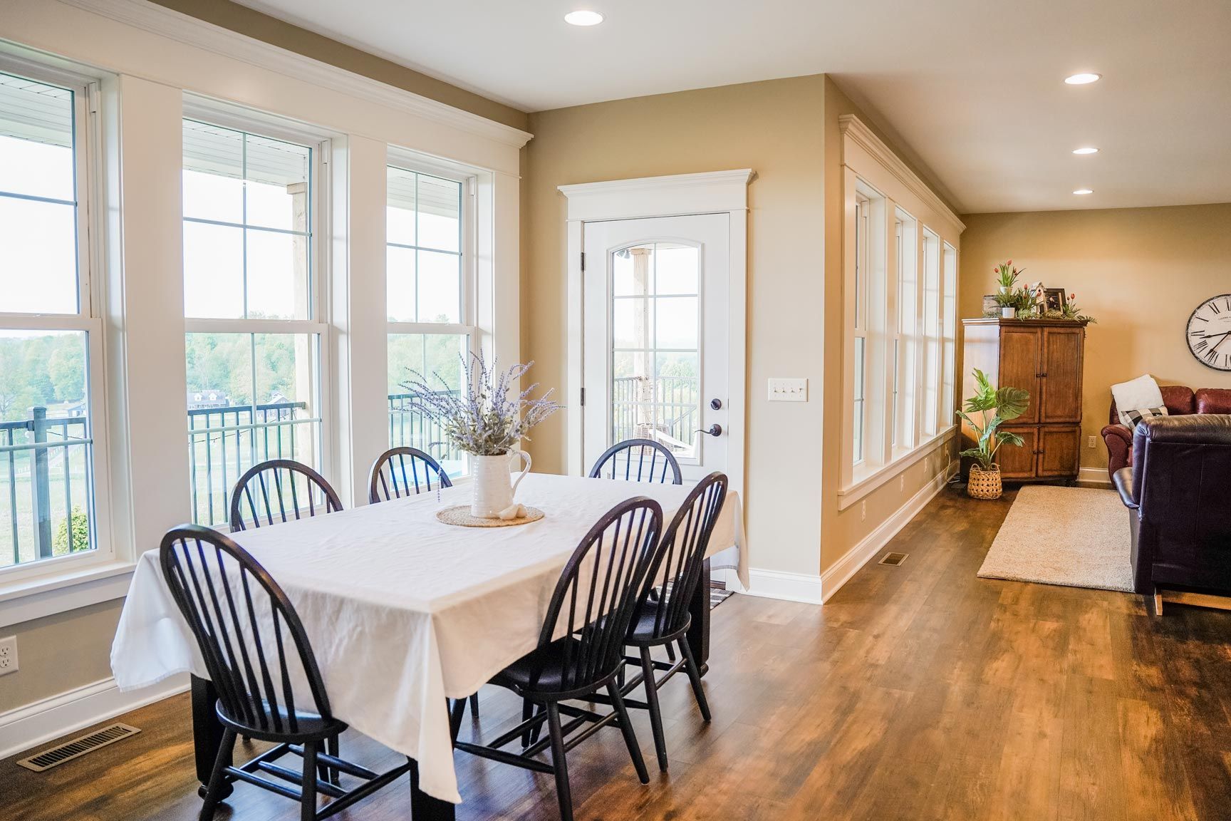 Dining room with table set for six, surrounded by windows and a doorway. Dark wood floor.