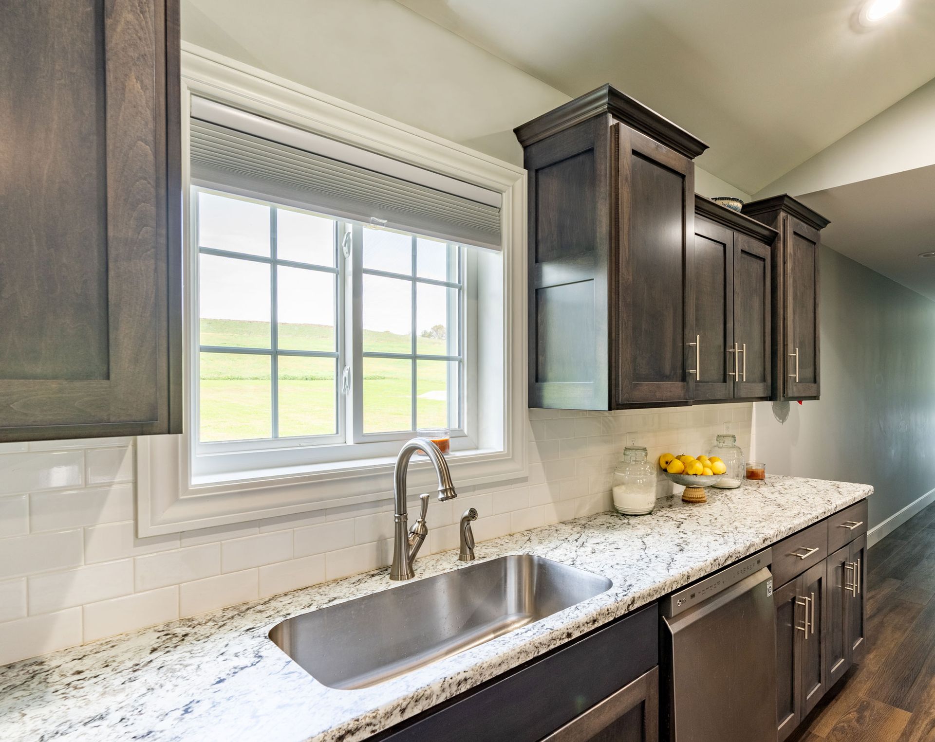 Kitchen with dark wood cabinets, stainless steel sink, and granite countertops.