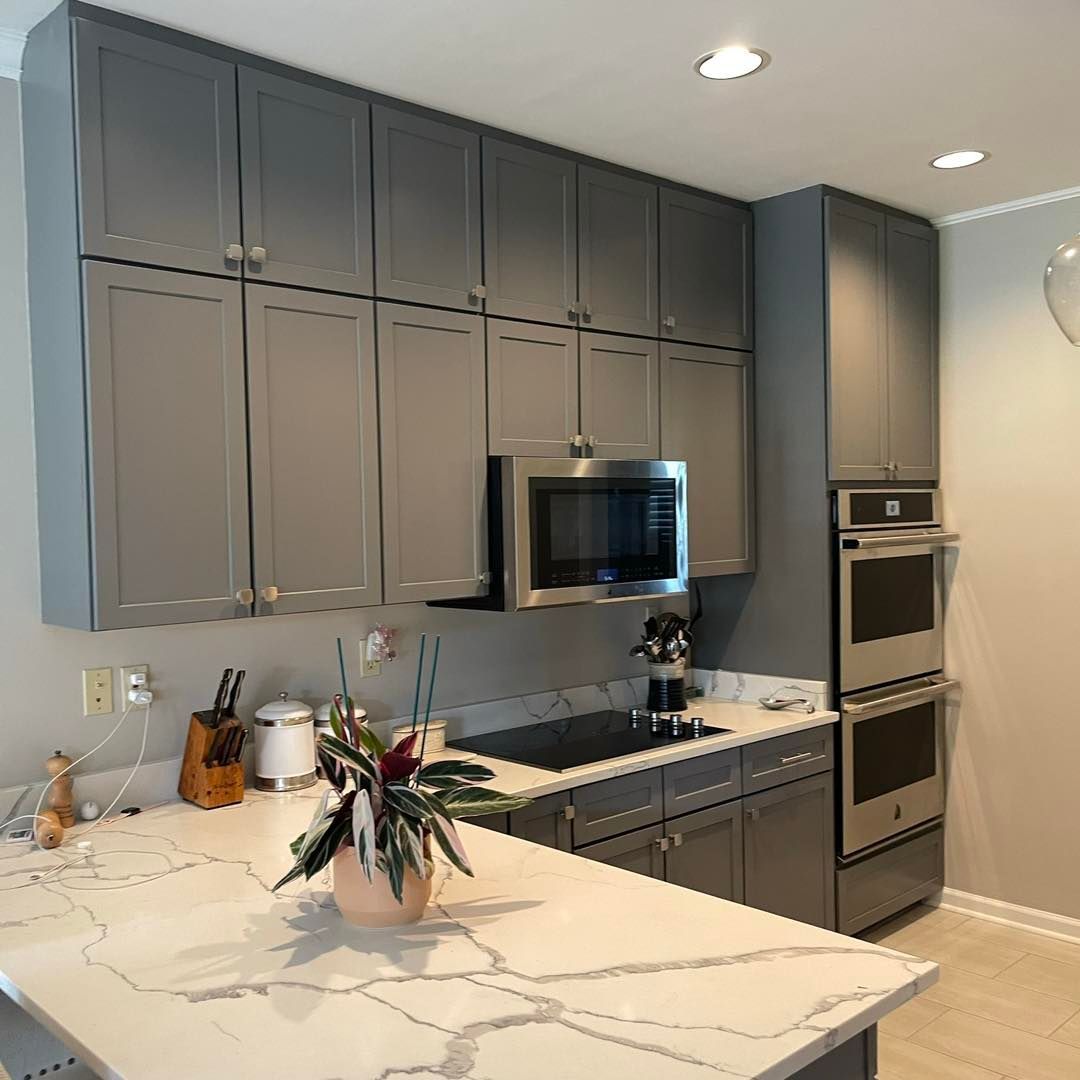 Gray kitchen with upper and lower cabinets, stainless steel appliances, and white countertop.