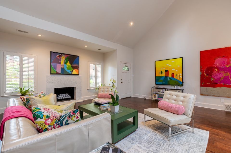 Living room with vibrant abstract art, white sofa, green coffee table, and wood floors.