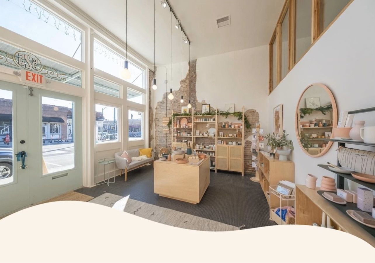 Bright interior of a store with wooden displays and shelves. Products are visible. Large windows let in sunlight.