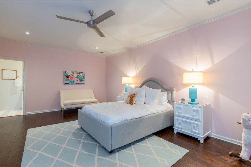 Pink bedroom with bed, nightstands, and blue rug.