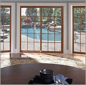 Sliding glass doors overlooking a pool. Wooden frames, grid pattern, sunny day. Table setting in foreground.