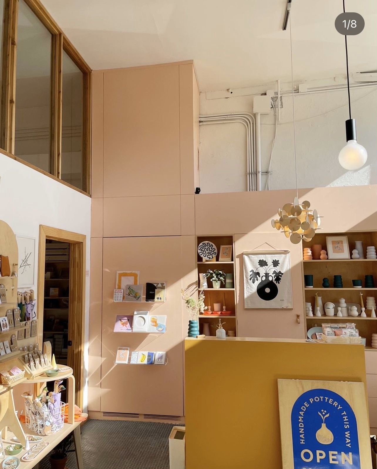Interior of a shop with pink walls, display shelves, and a yellow counter. Open sign visible.