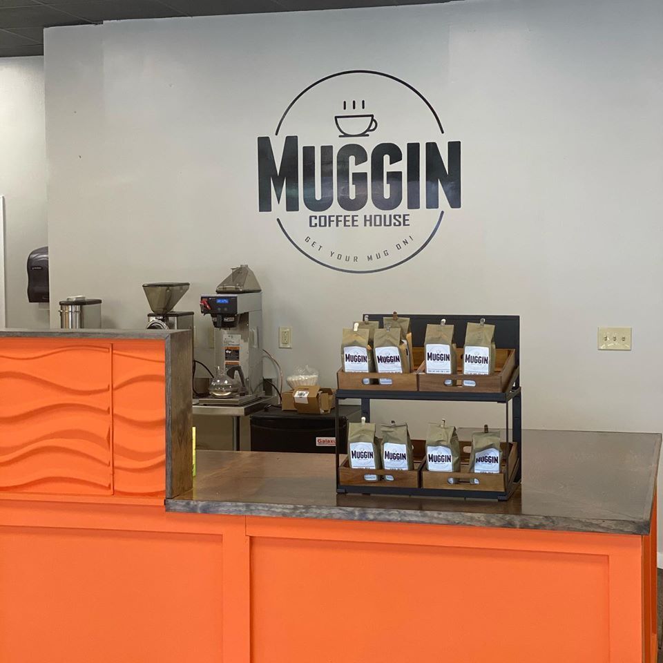 Interior of Muggin Coffee House with coffee bags and orange counter.