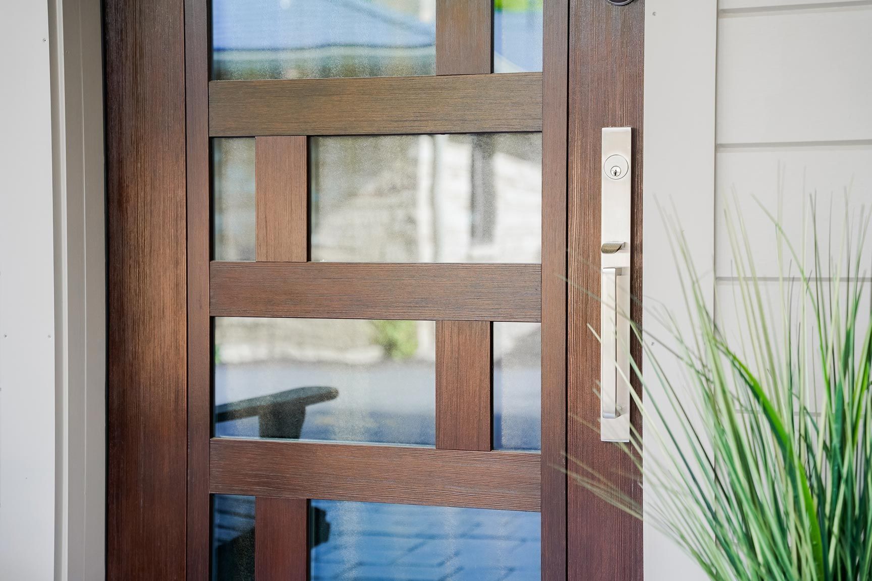 Wooden front door with glass panels and a silver handle.