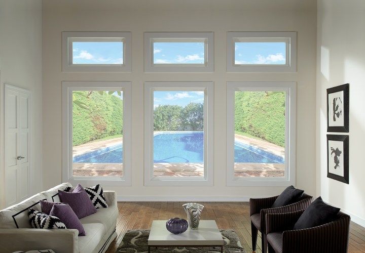 Living room with large windows overlooking a pool, light walls, and hardwood floors.