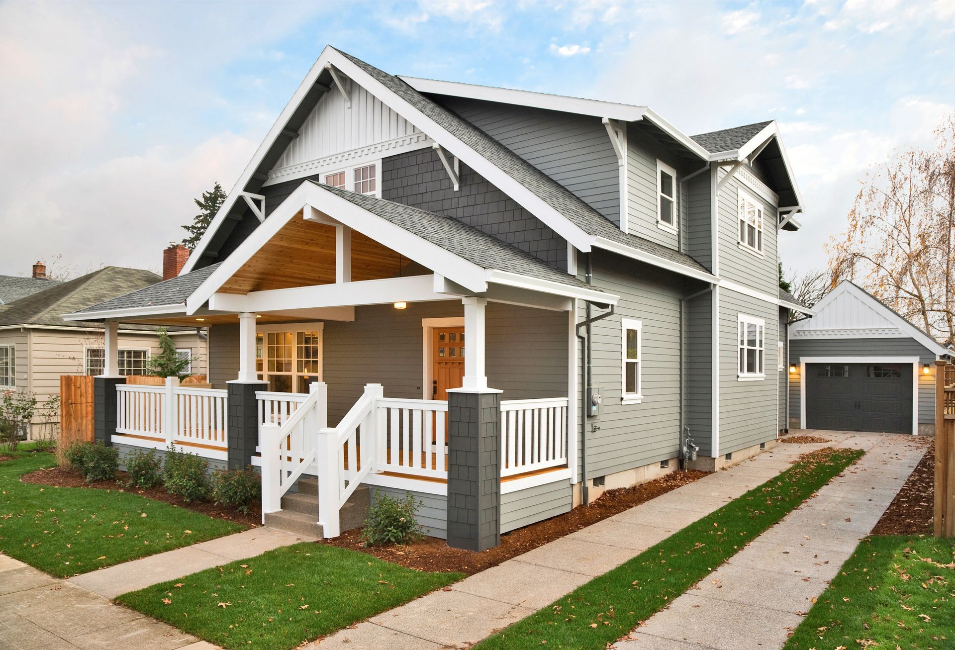 Gray two-story house with white trim and a small garage; driveway leads to the garage and the front porch.