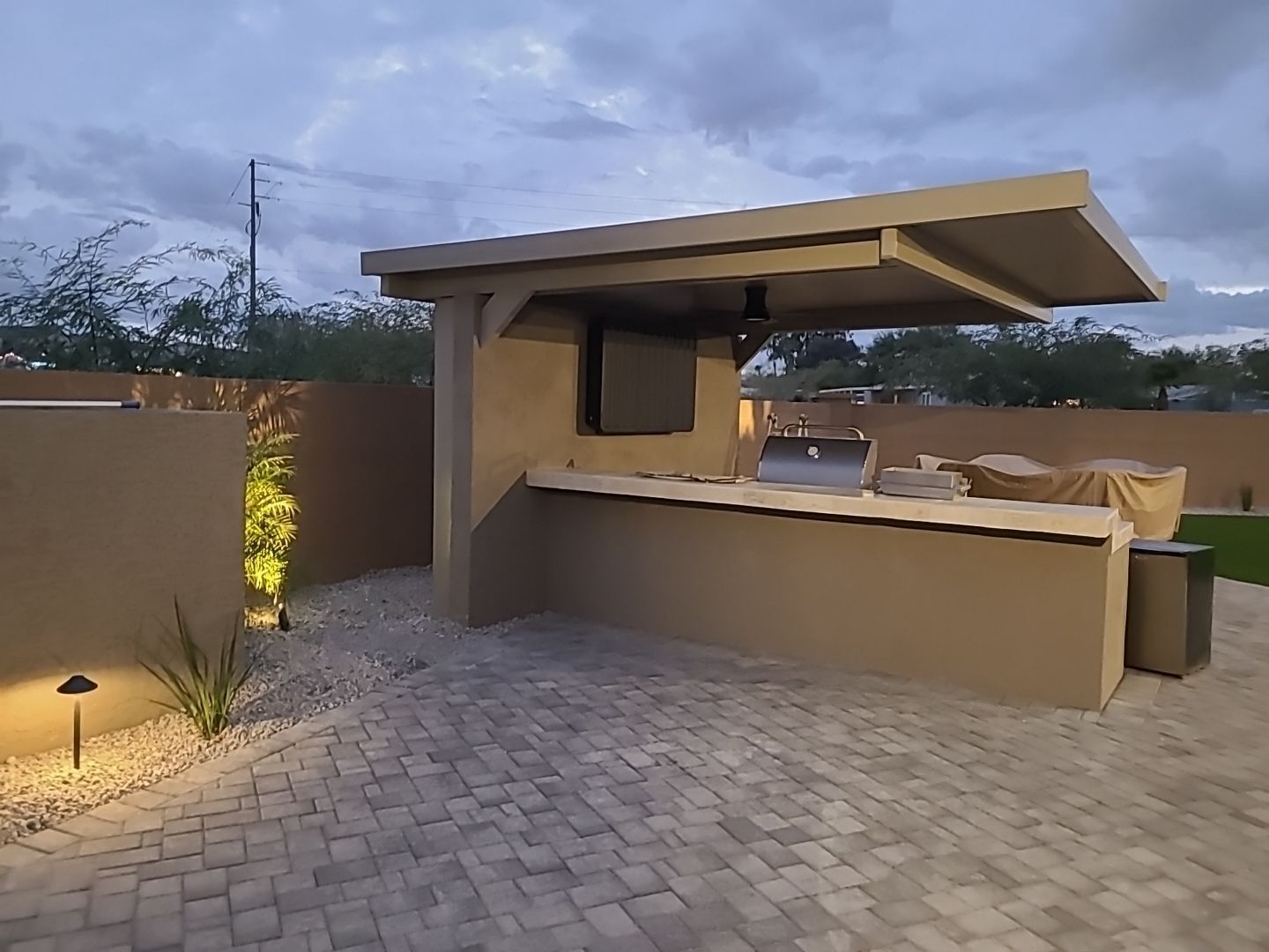 An outdoor kitchen with a grill and a roof