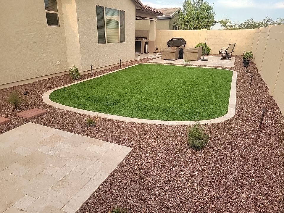 A backyard with a lush green lawn and patio furniture.