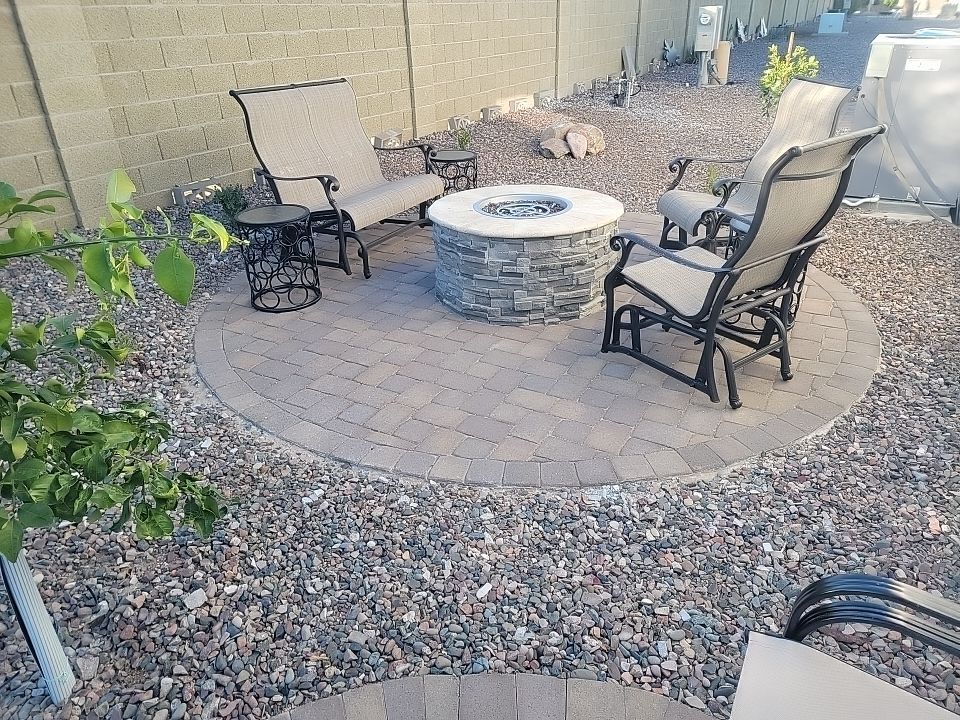 There is a fire pit in the middle of the patio with chairs around it.