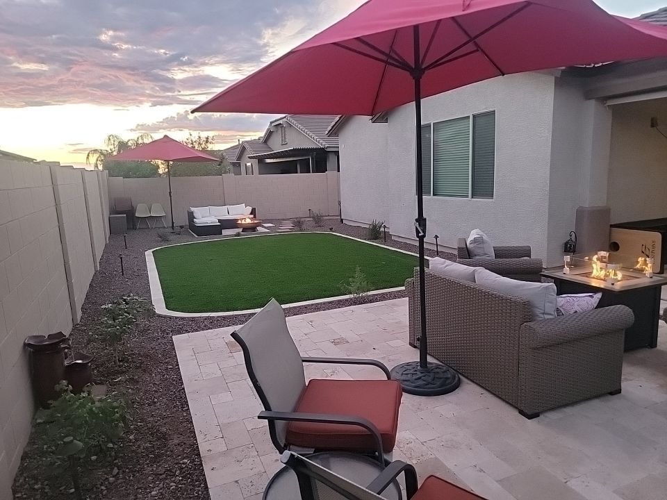 A patio with a red umbrella and chairs in front of a house.
