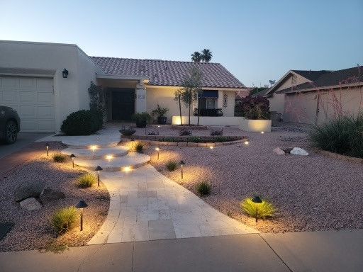 A house with a walkway leading to it is lit up at night.
