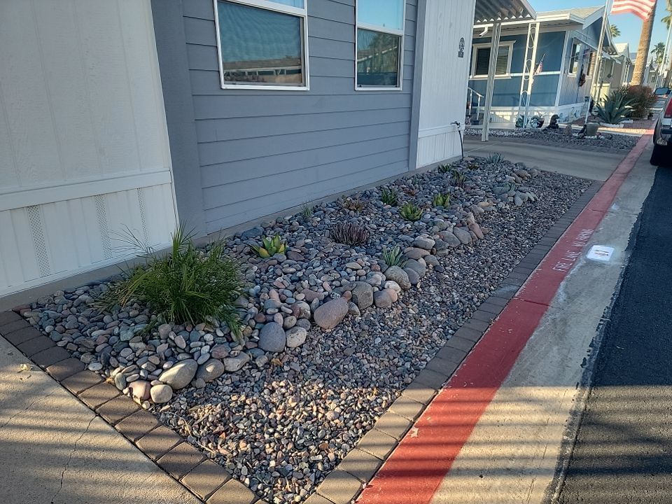 A yard with rocks and plants in front of a house