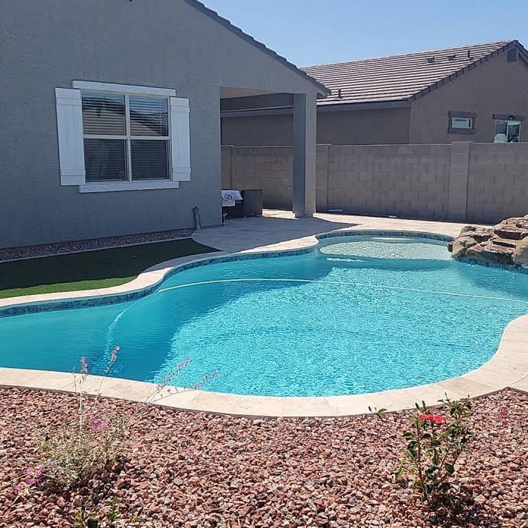 A large swimming pool is in the backyard of a house.