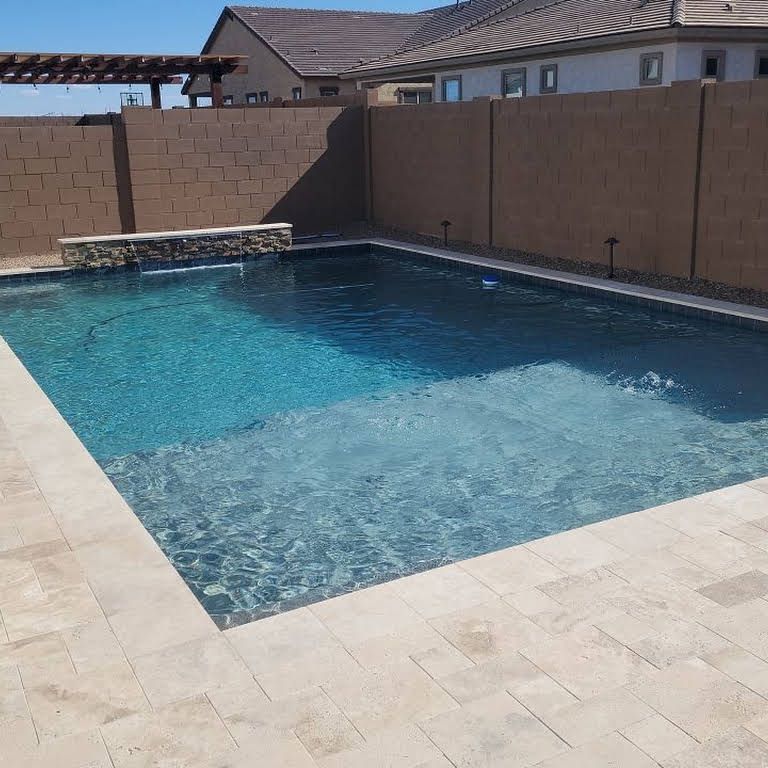 A large swimming pool is surrounded by a brick wall