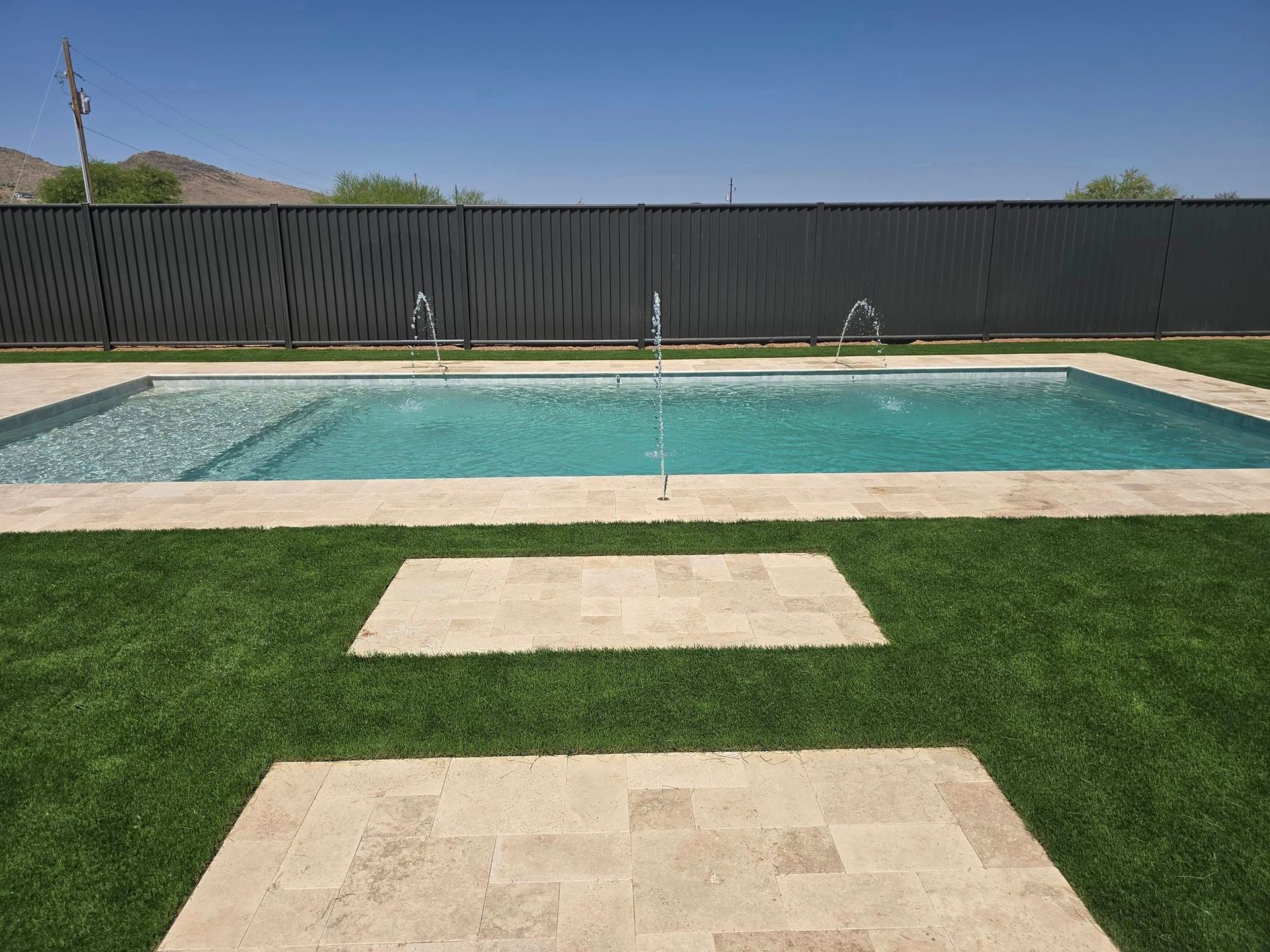 A large swimming pool surrounded by grass and a fence.