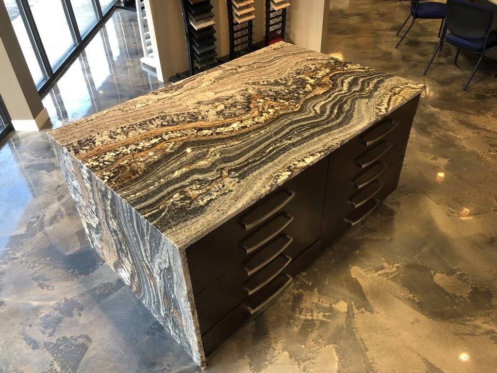 Kitchen island with striped granite countertop and dark brown cabinets.