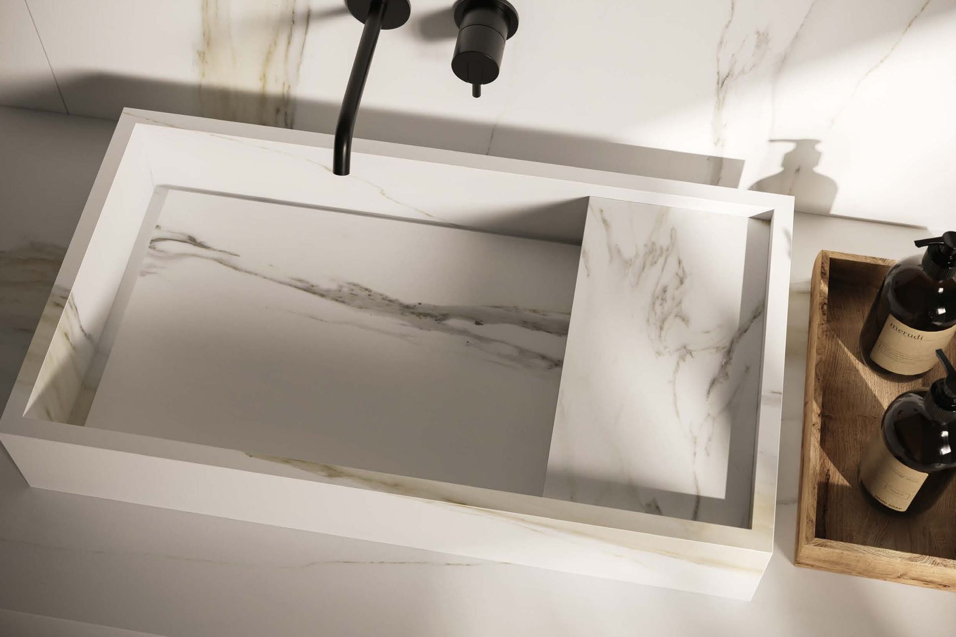 White marble kitchen sink with black faucet and soap bottles on a wooden tray