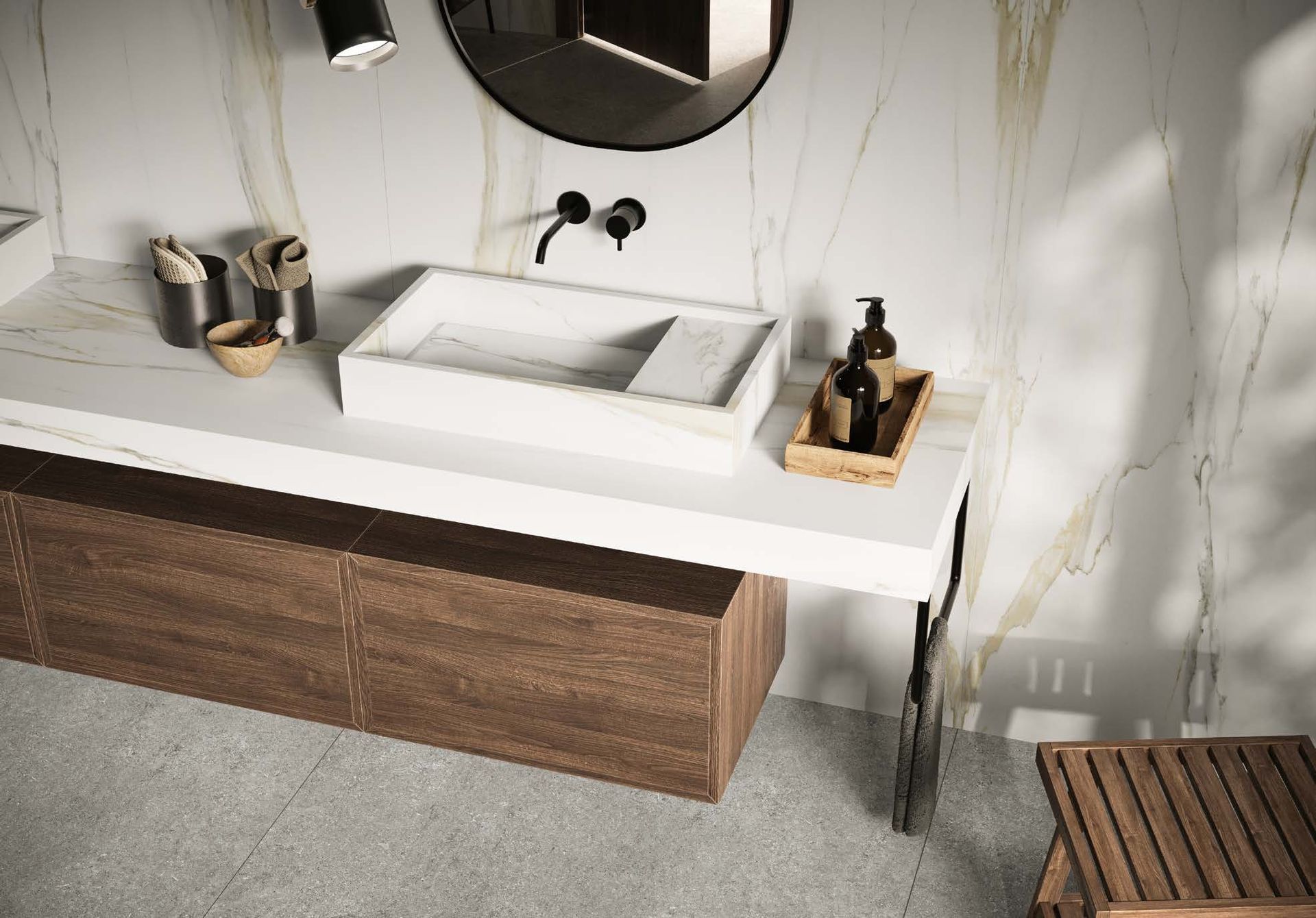 Modern bathroom vanity with white sink, wood cabinet, and black fixtures against a marble wall.