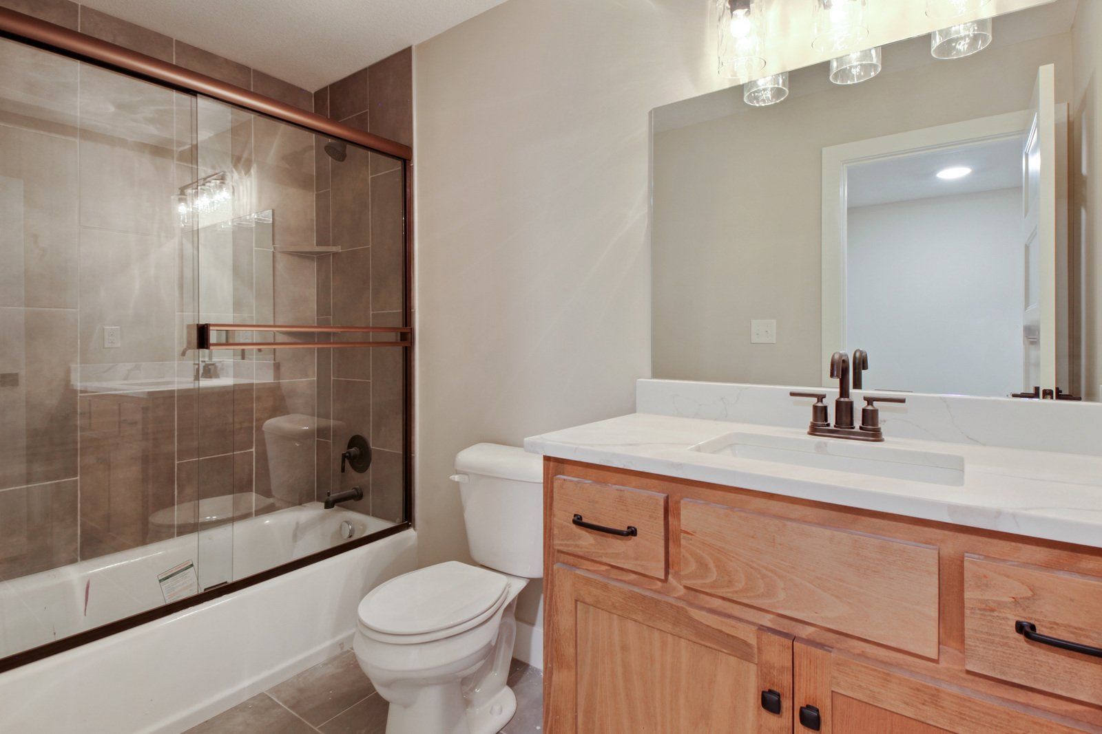 A bathroom with a toilet , sink , tub and mirror.