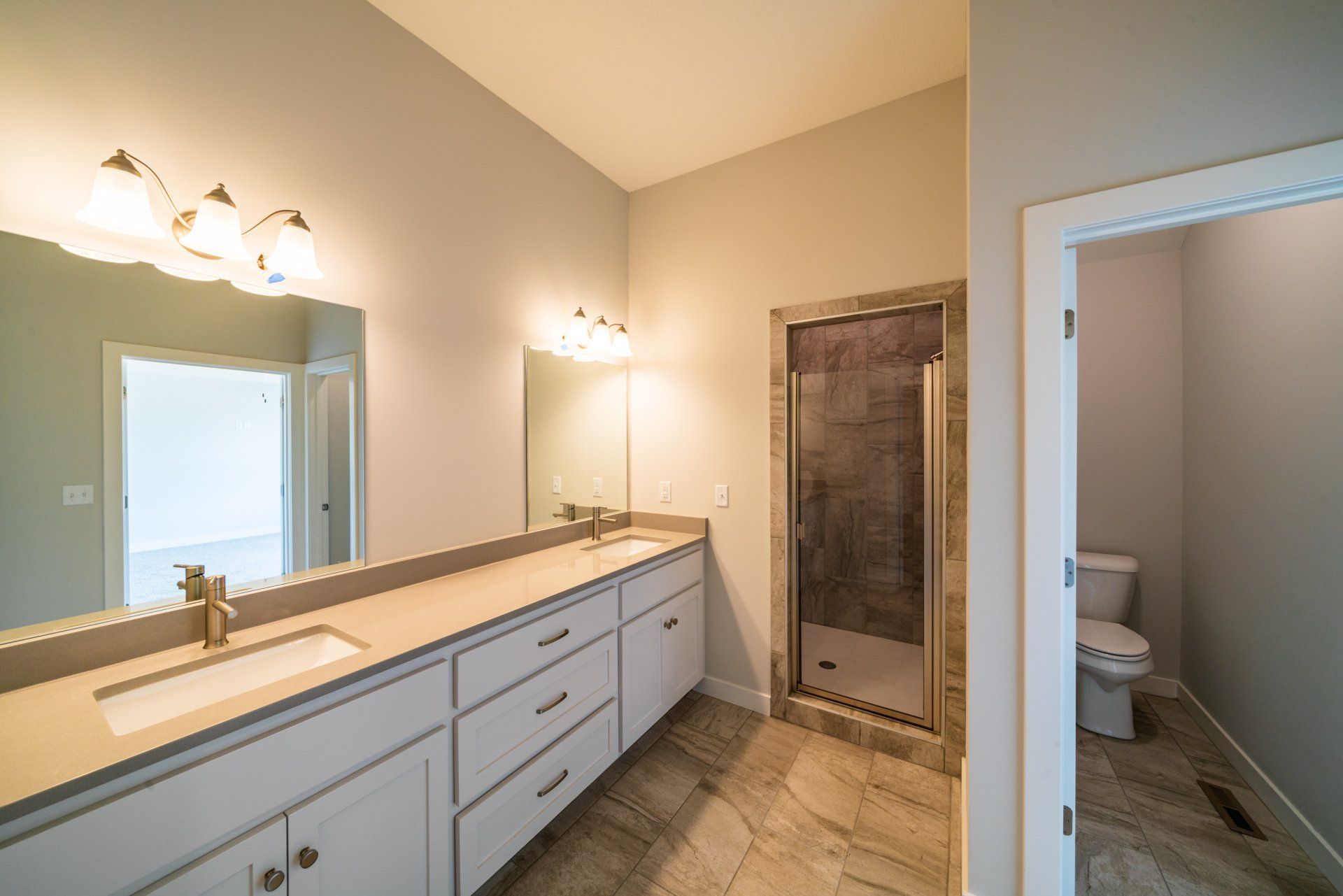 A bathroom with two sinks , a toilet , and a walk in shower.