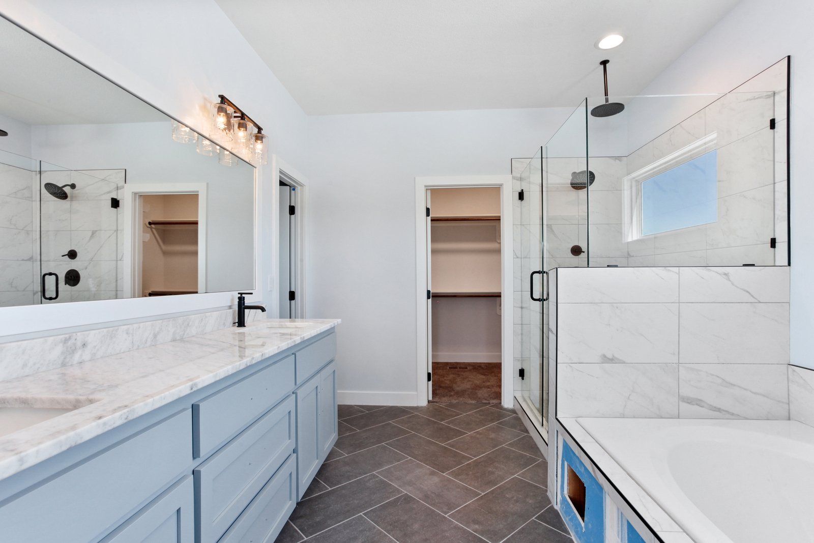 A bathroom with two sinks , a tub , and a walk in closet.