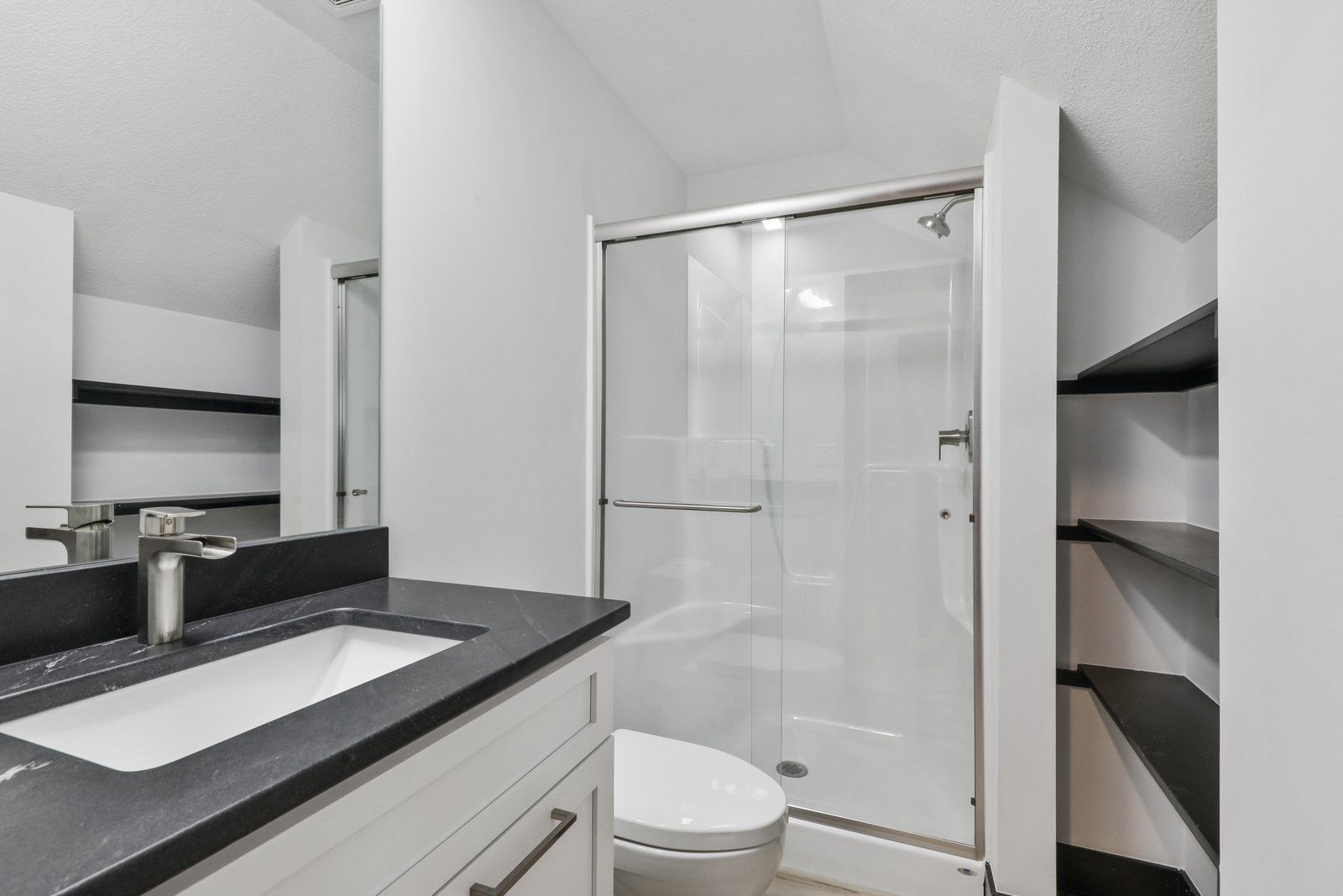 A bathroom with a toilet , sink and shower.