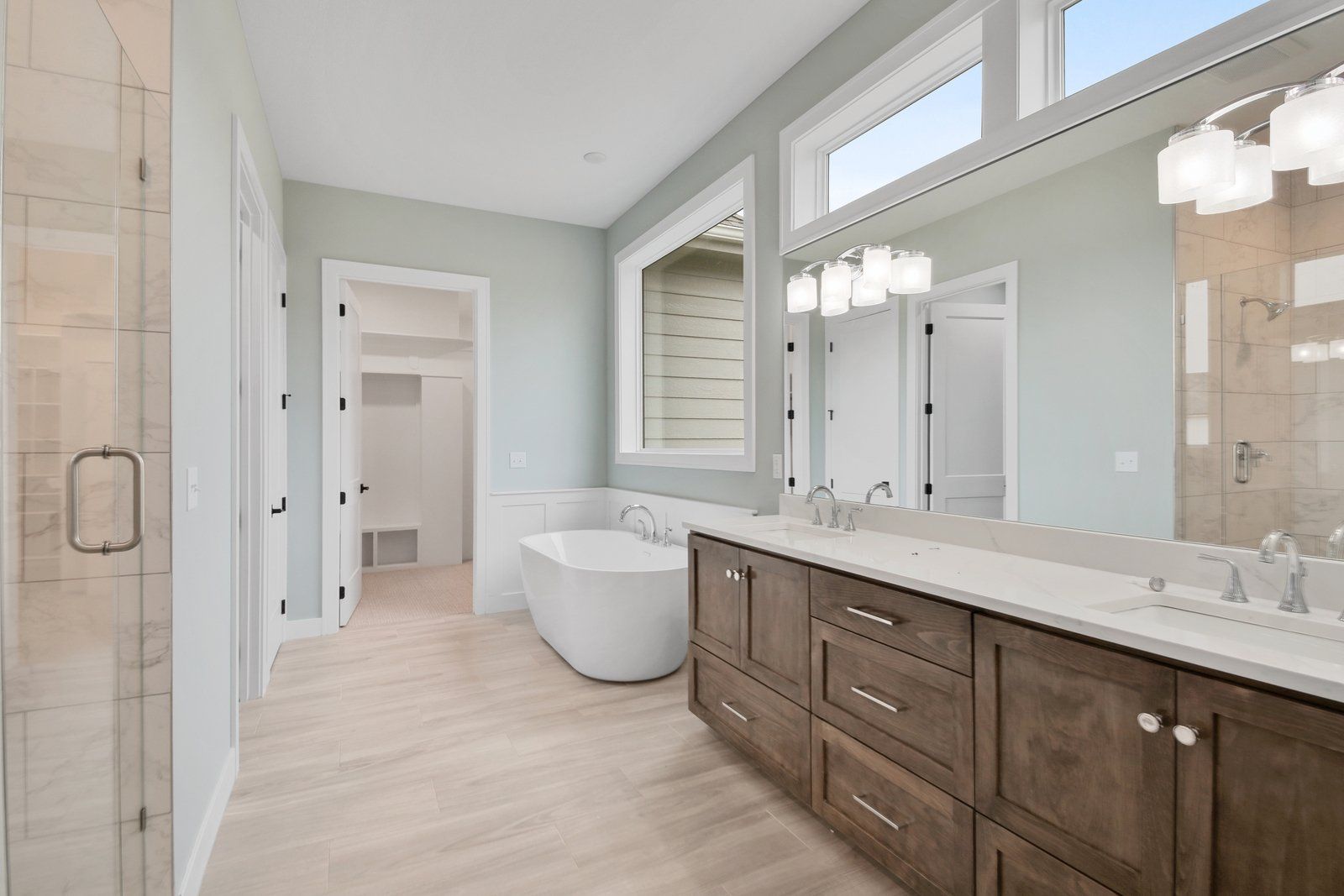 A bathroom with two sinks , a tub , and a large mirror.