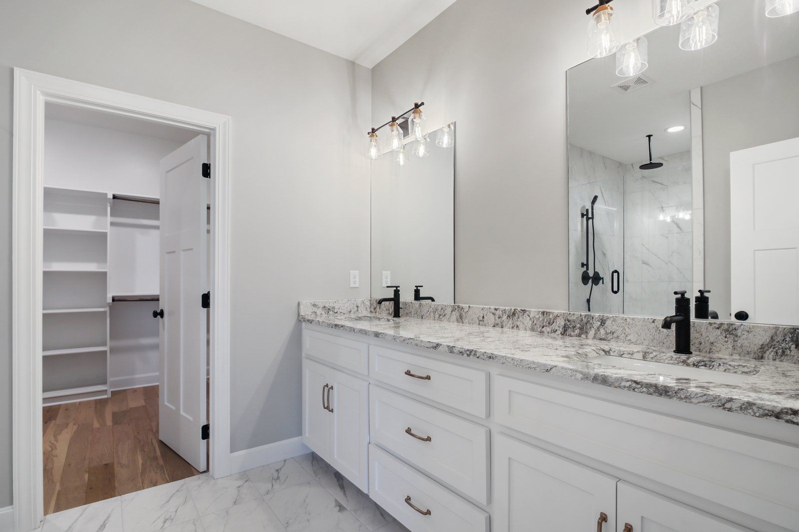 A bathroom with two sinks , a mirror and a walk in closet.