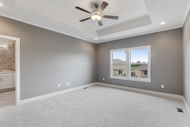An empty bedroom with a ceiling fan and two windows.