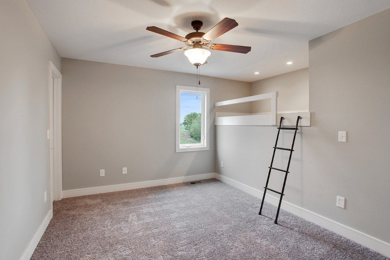 An empty bedroom with a bunk bed and a ceiling fan.