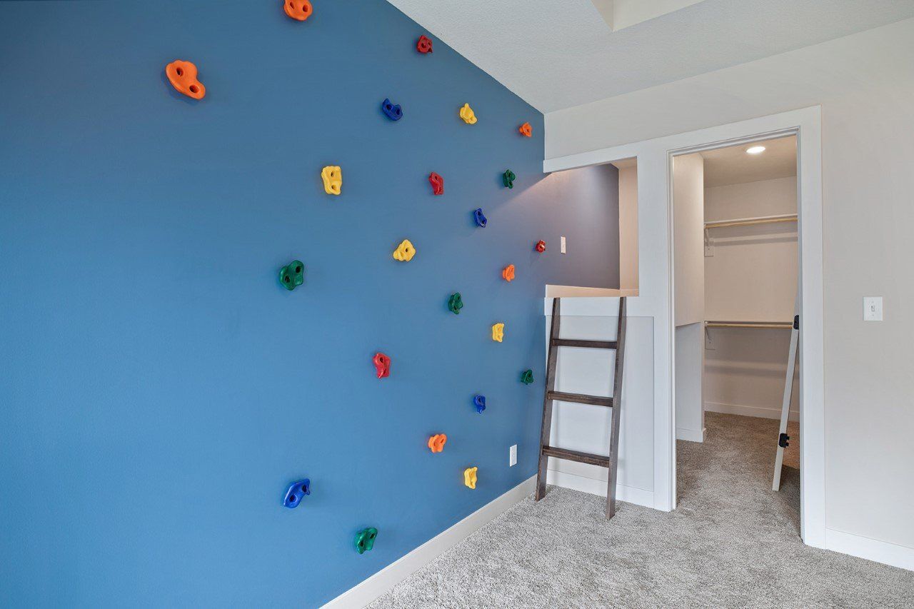 A bedroom with a climbing wall and a ladder.