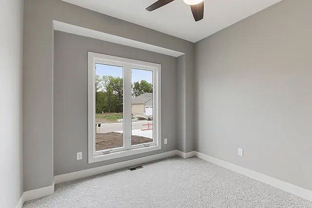 An empty bedroom with a ceiling fan and a large window.