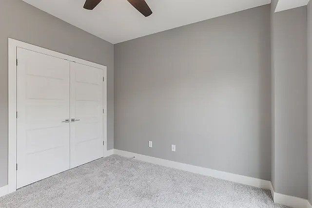 An empty bedroom with gray walls and a ceiling fan.