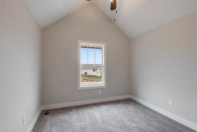 An empty bedroom with a vaulted ceiling and a window.