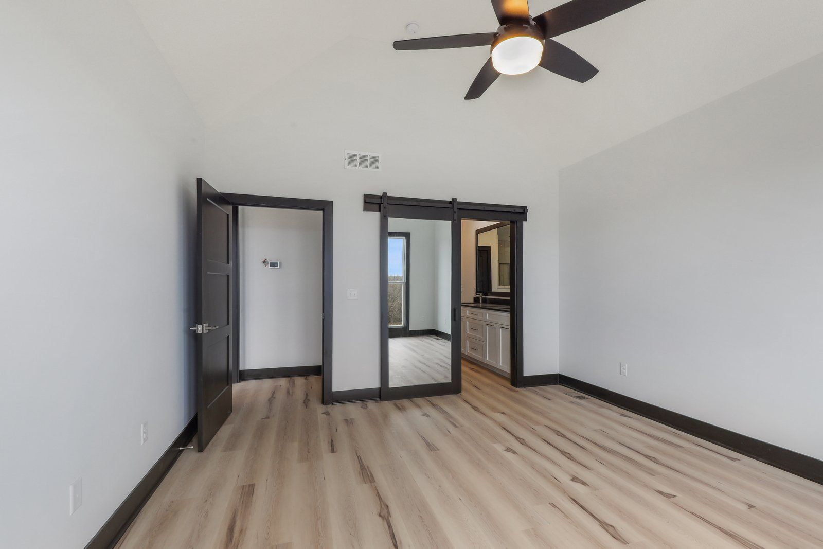 An empty room with hardwood floors and a ceiling fan