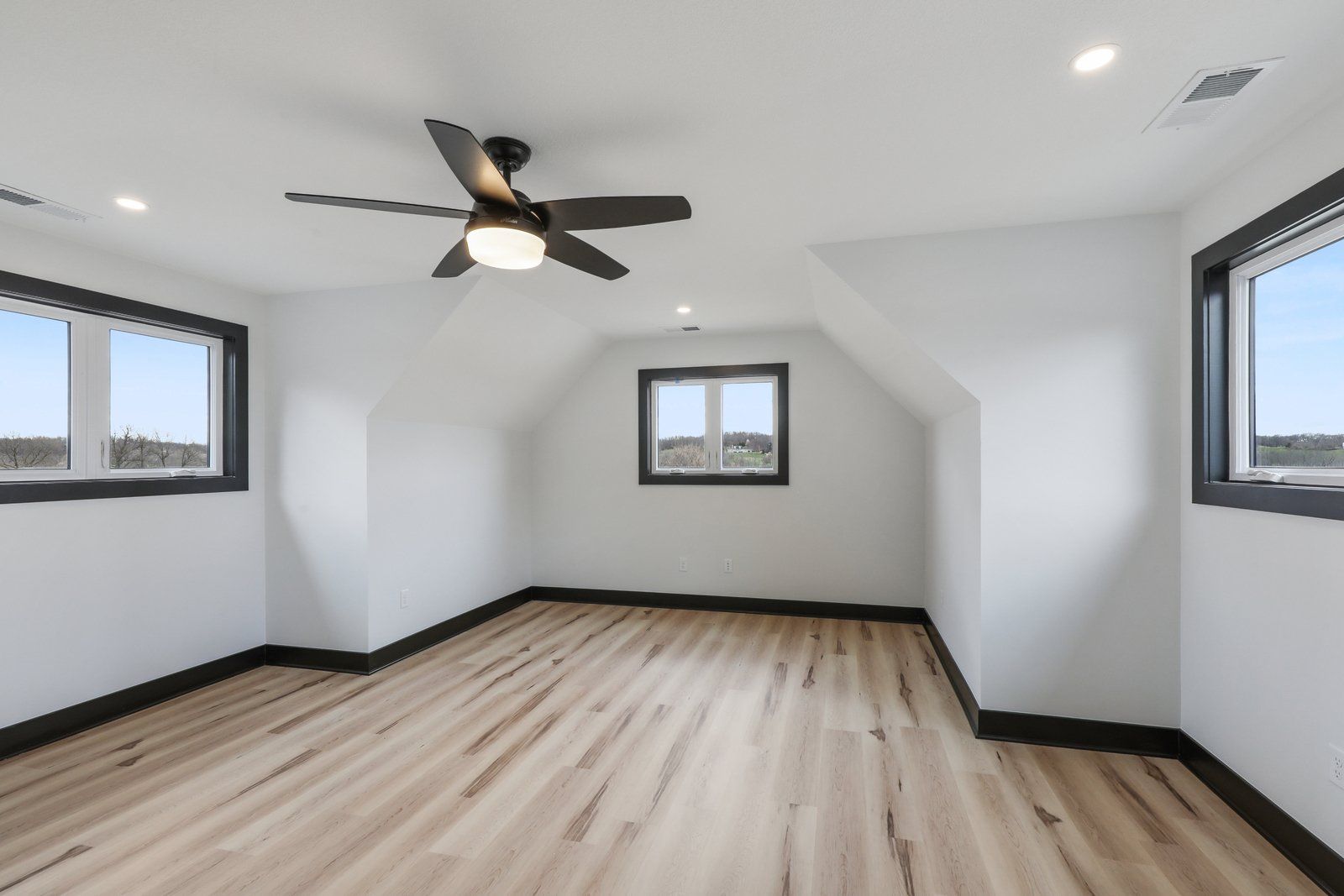 An empty room with hardwood floors and a ceiling fan
