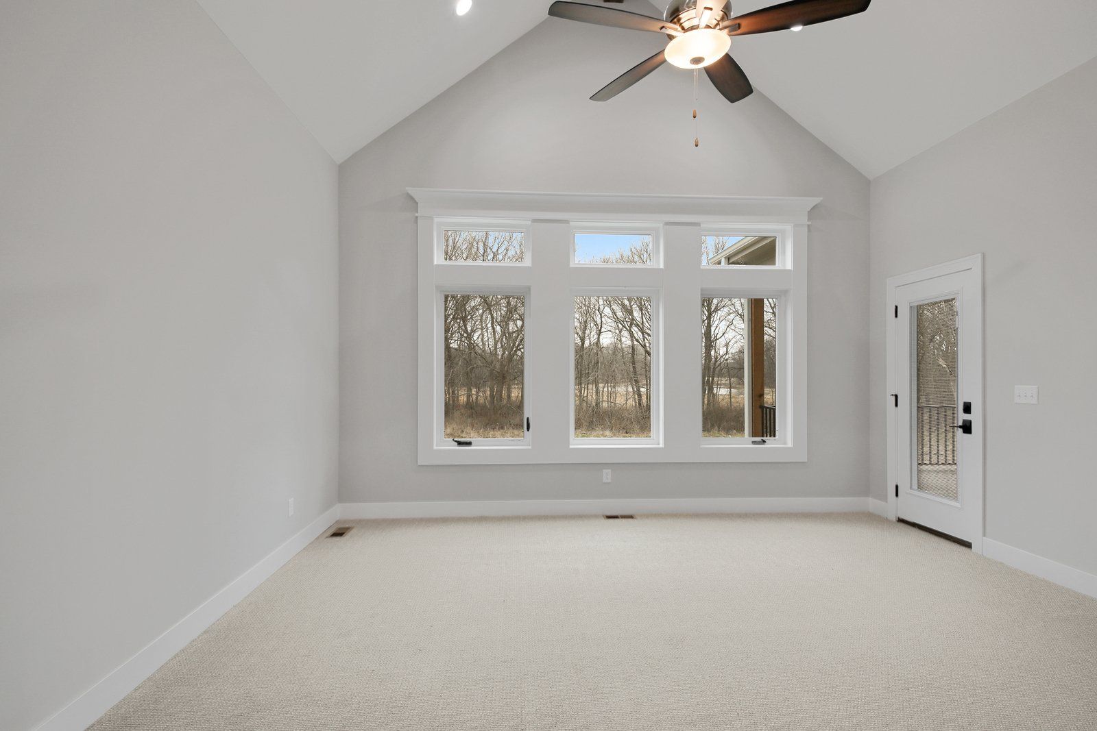 An empty room with a vaulted ceiling and a ceiling fan.