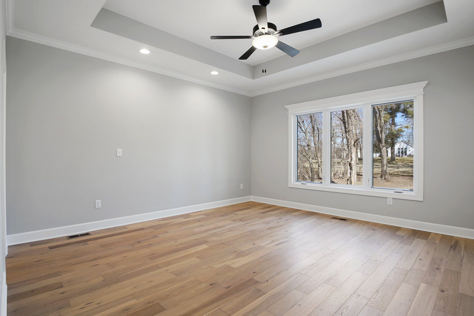 An empty room with hardwood floors and a ceiling fan.
