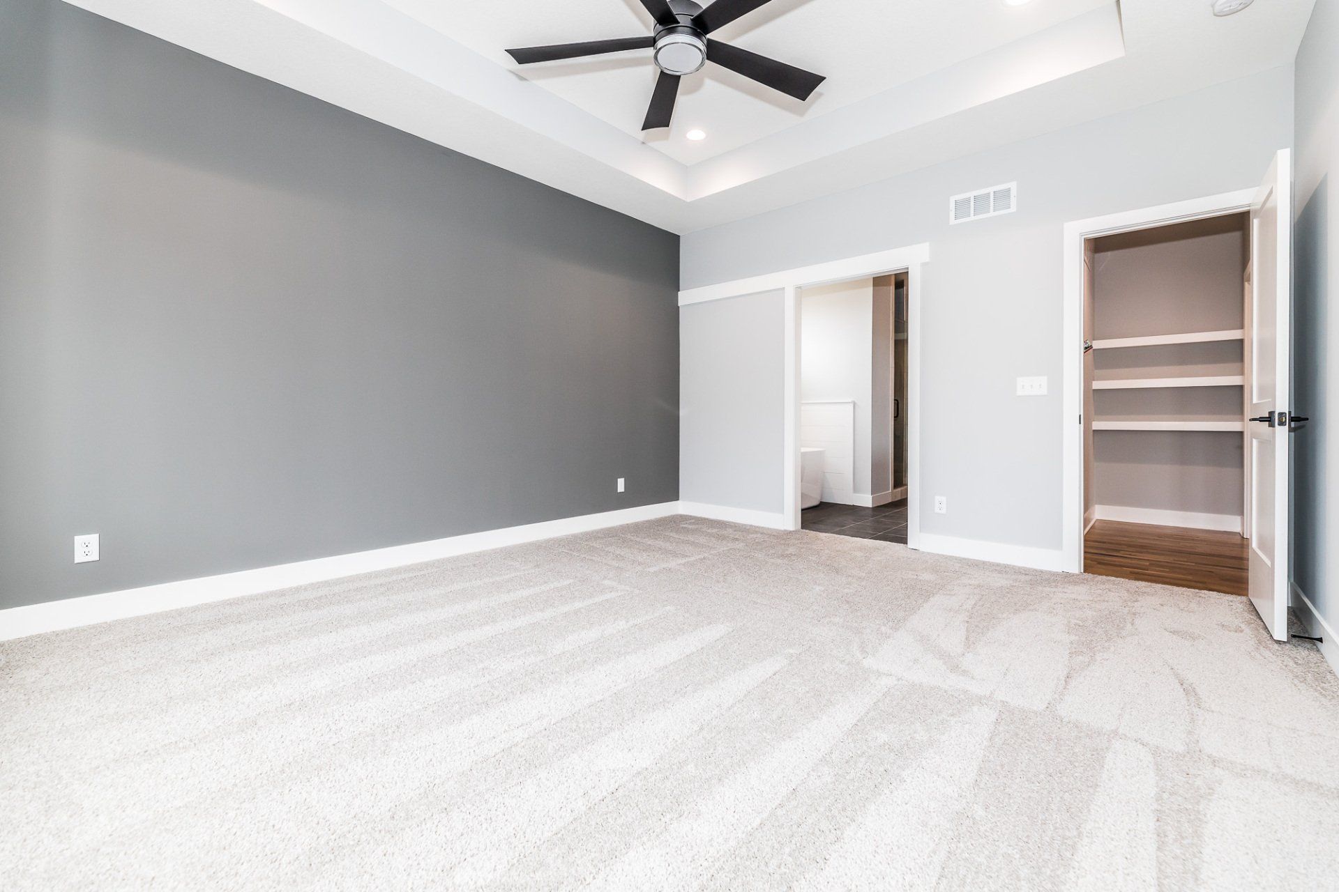 An empty bedroom with a ceiling fan and a closet.