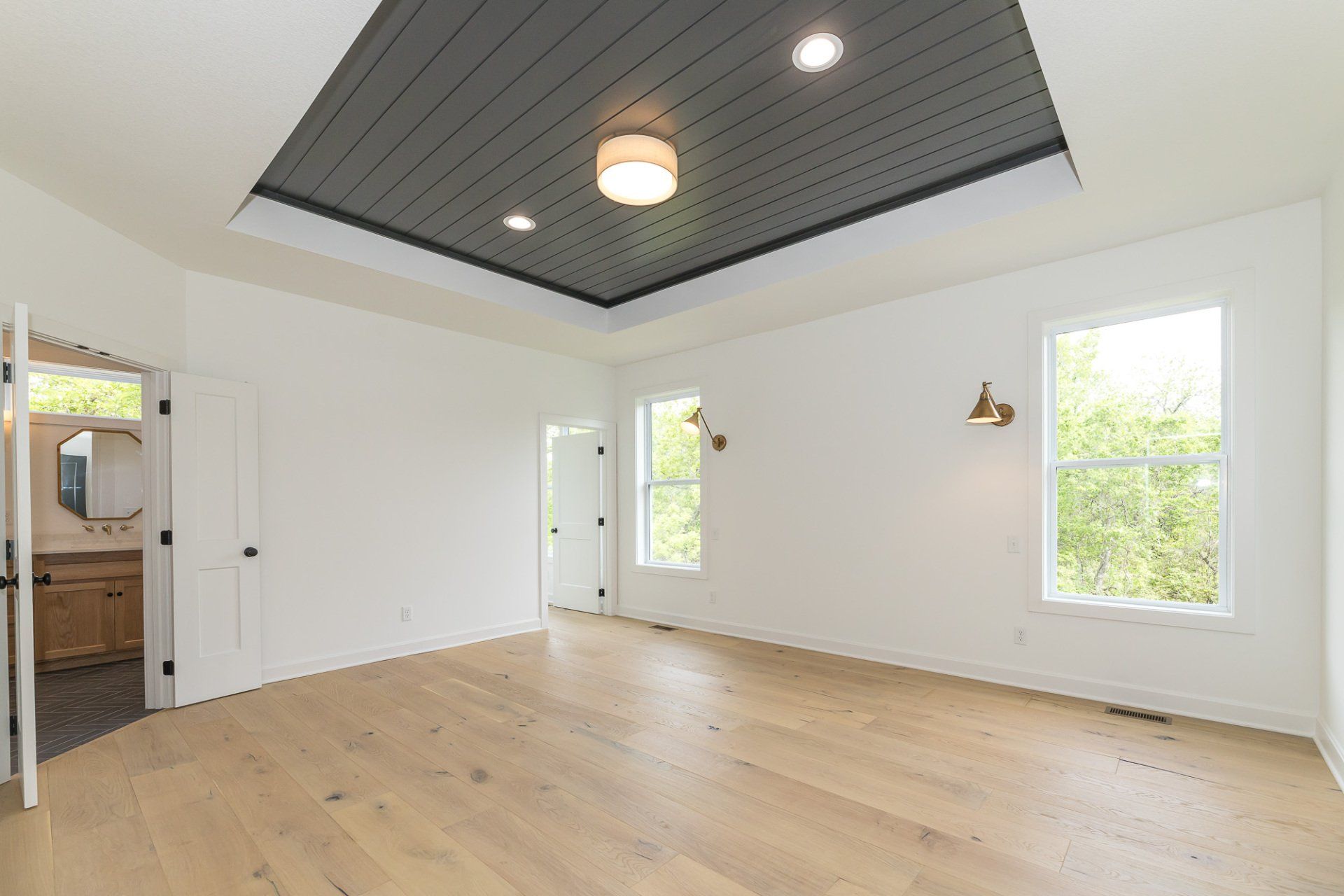 A large empty room with hardwood floors and a black ceiling.
