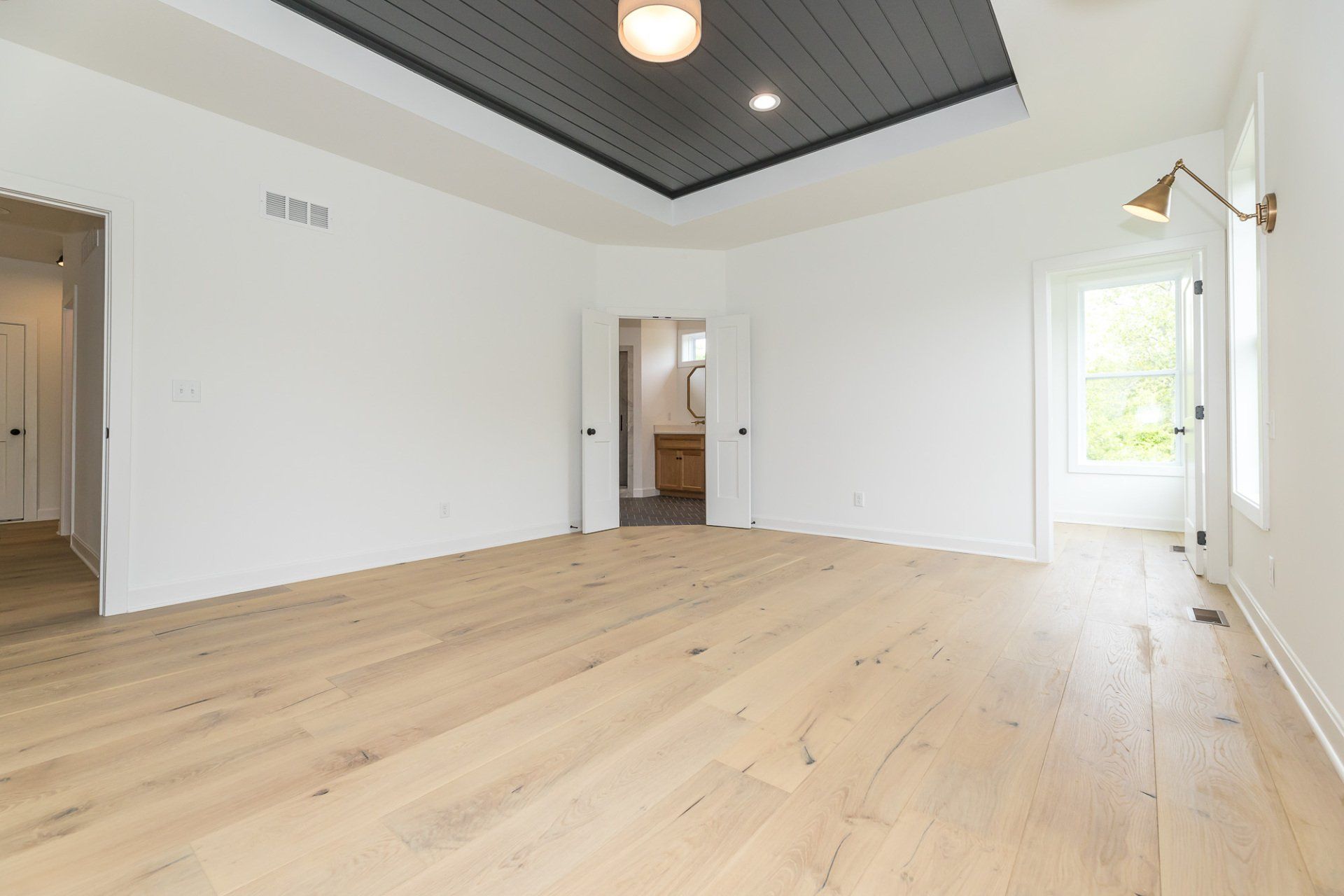 A large empty room with hardwood floors and a black ceiling.