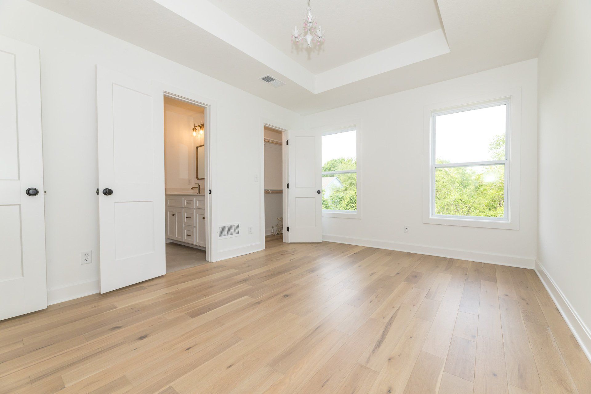 An empty bedroom with hardwood floors and white walls.