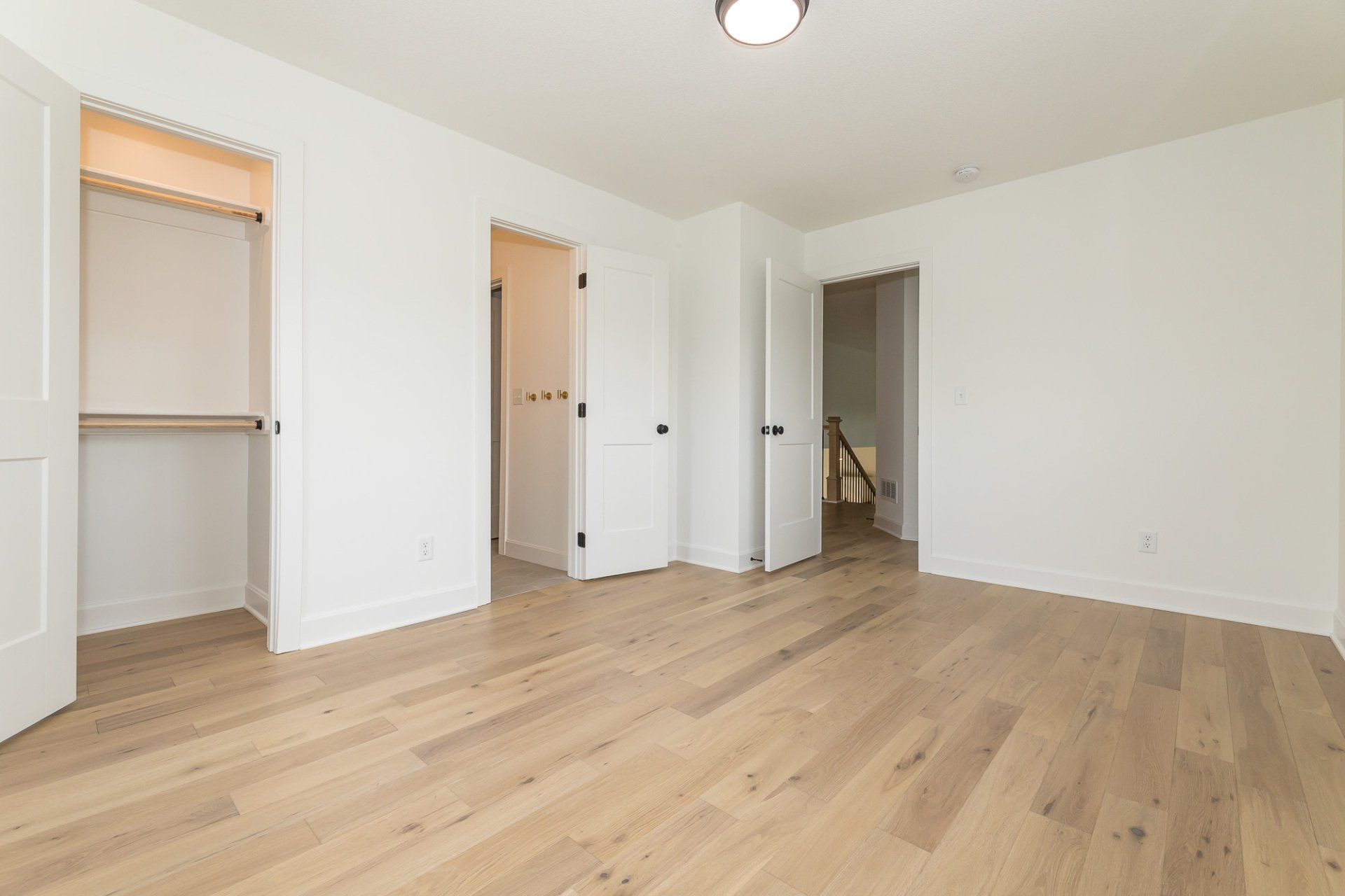 An empty bedroom with hardwood floors and white walls.