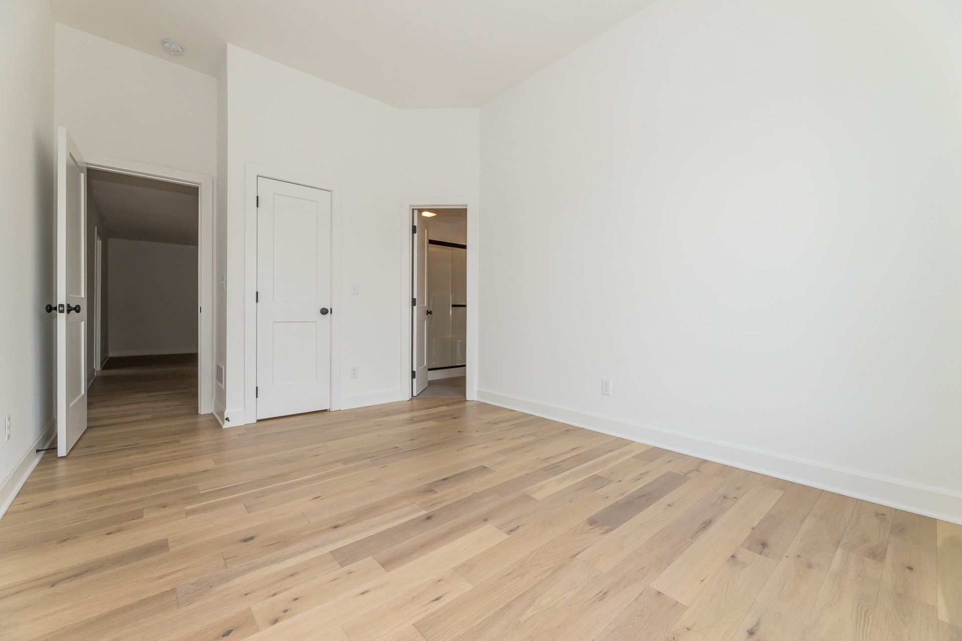 A large empty room with hardwood floors and white walls.