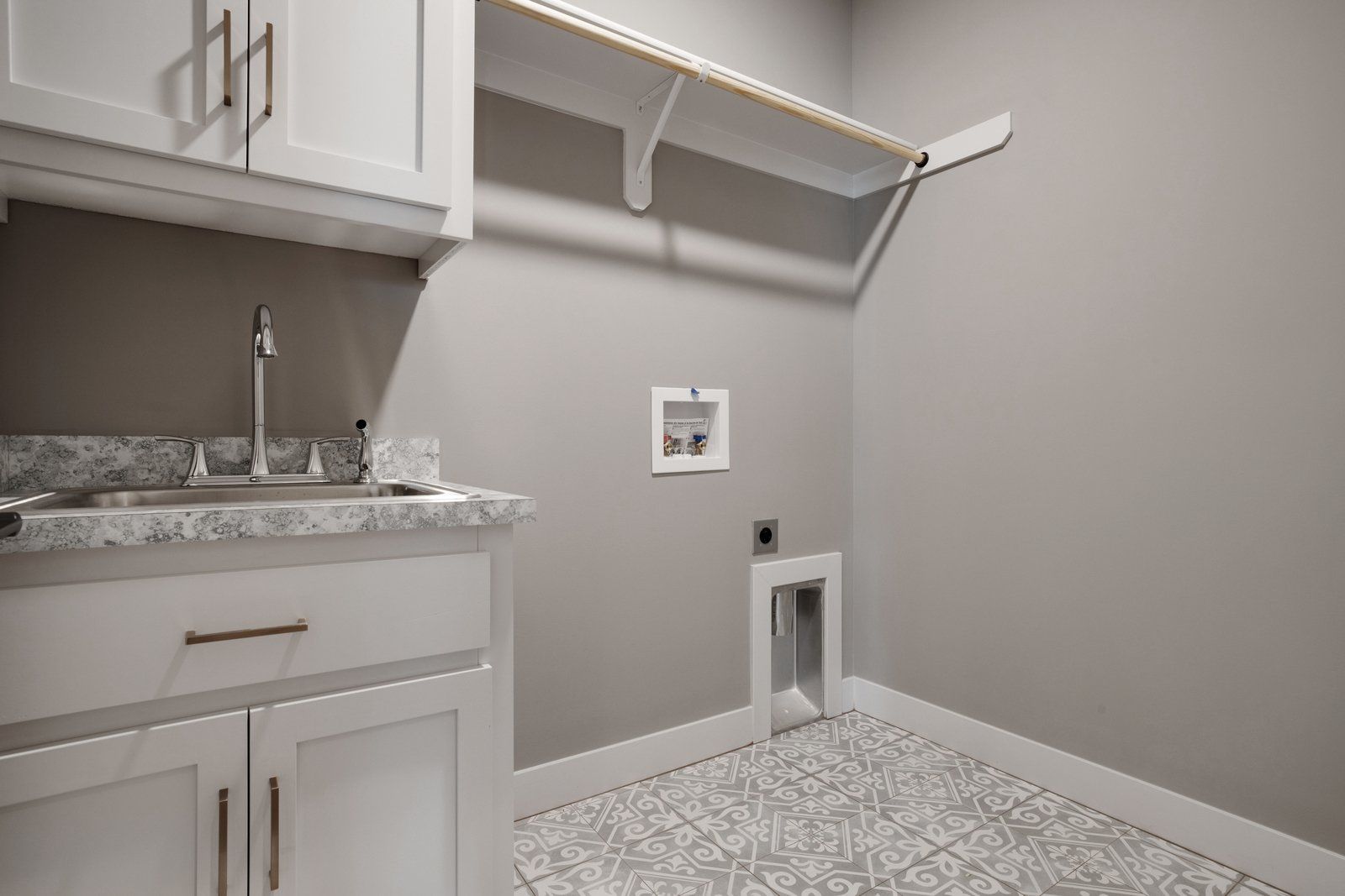 A laundry room with a sink , cabinets , and a shelf.