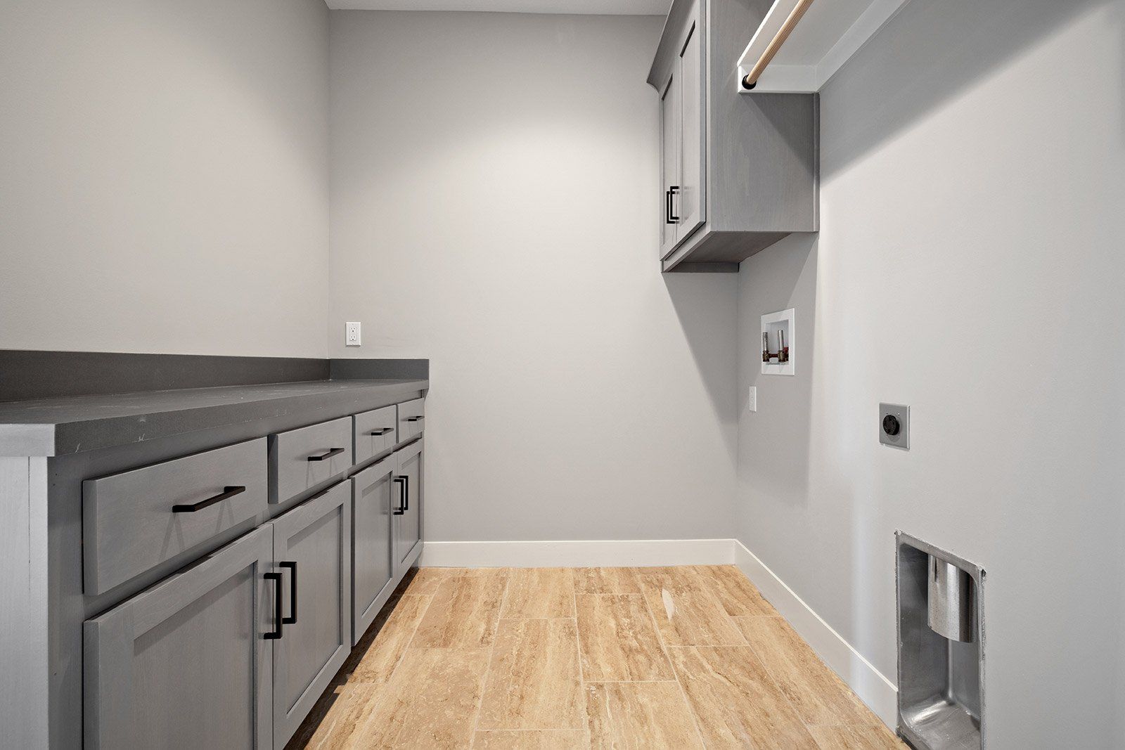 A laundry room with gray cabinets and wooden floors.
