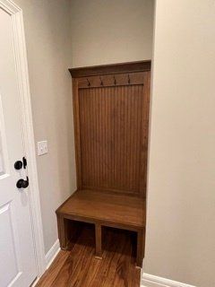 A hallway with a wooden bench and a coat rack.