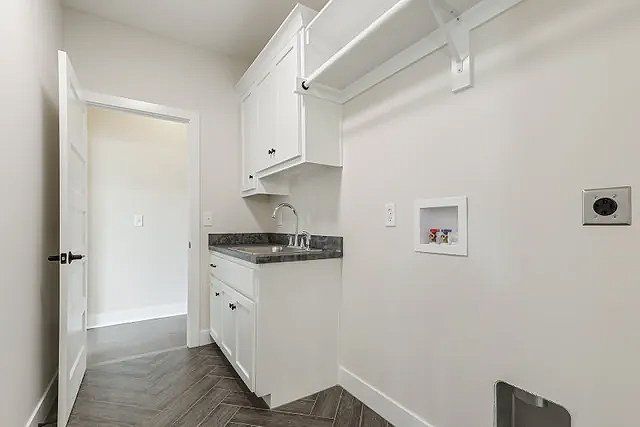A laundry room with white cabinets , a sink , and a washer and dryer.